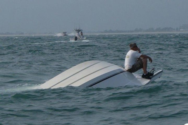 a man riding on the back of a white boat in the middle of the ocean