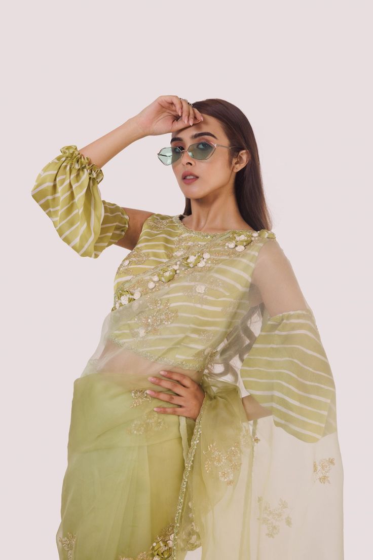 The stylish green organza saree with cold-shoulder balloon-sleeved blouse, embroidered with cut dana, off-white stripes blouse. Shop designer saris online in the USA from Pure Elegance. Disclaimer: The actual product may vary slightly from the image. These are custom orders, hence expect slight variation in color and placement of the motif or buta. ESTIMATED DELIVERYBecause this is a custom order, it would take about 4 weeks from the date of purchase. RETURN POLICYThis product is a custom order and cannot be returned or exchanged. Designer Organza Blouse For Party Wear, Designer Organza Party Wear Blouse, Party Wear Organza Blouse With Resham Embroidery, Organza Blouse For Designer Party Wear, Party Wear Chanderi Blouse With Resham Embroidery, Organza Blouse For Party Wear, Party Wear Organza Blouse With Zari Work, Organza Party Blouse With Zari Work, Pista Green Organza Pre-draped Saree For Diwali