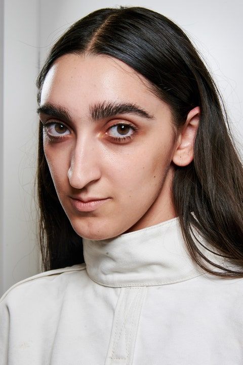 a woman with long hair wearing a white turtle neck sweater and black eyeliners