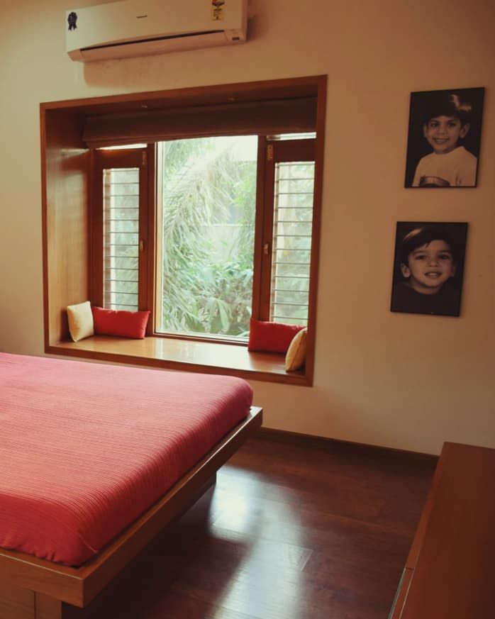 a bed sitting in a bedroom next to a window with pictures on the wall above it