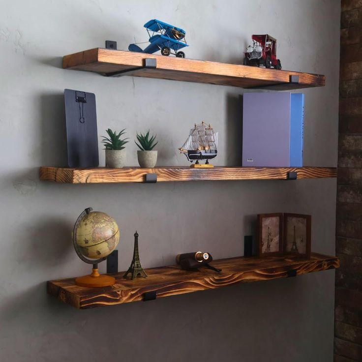 two wooden shelves on the wall with various items in front of them and one shelf holding a globe