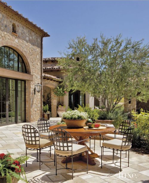 an outdoor dining table with four chairs and a potted plant in the middle of it