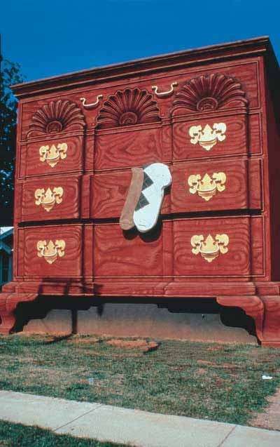 an ornately decorated chest of drawers on display in front of a building with blue sky