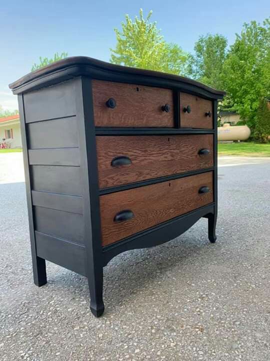 a black and brown dresser sitting in the middle of a road with trees behind it