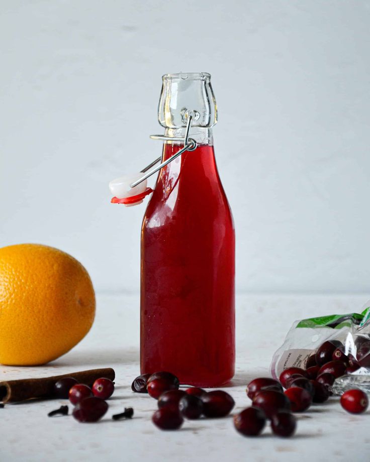 a bottle of cranberry juice next to an orange