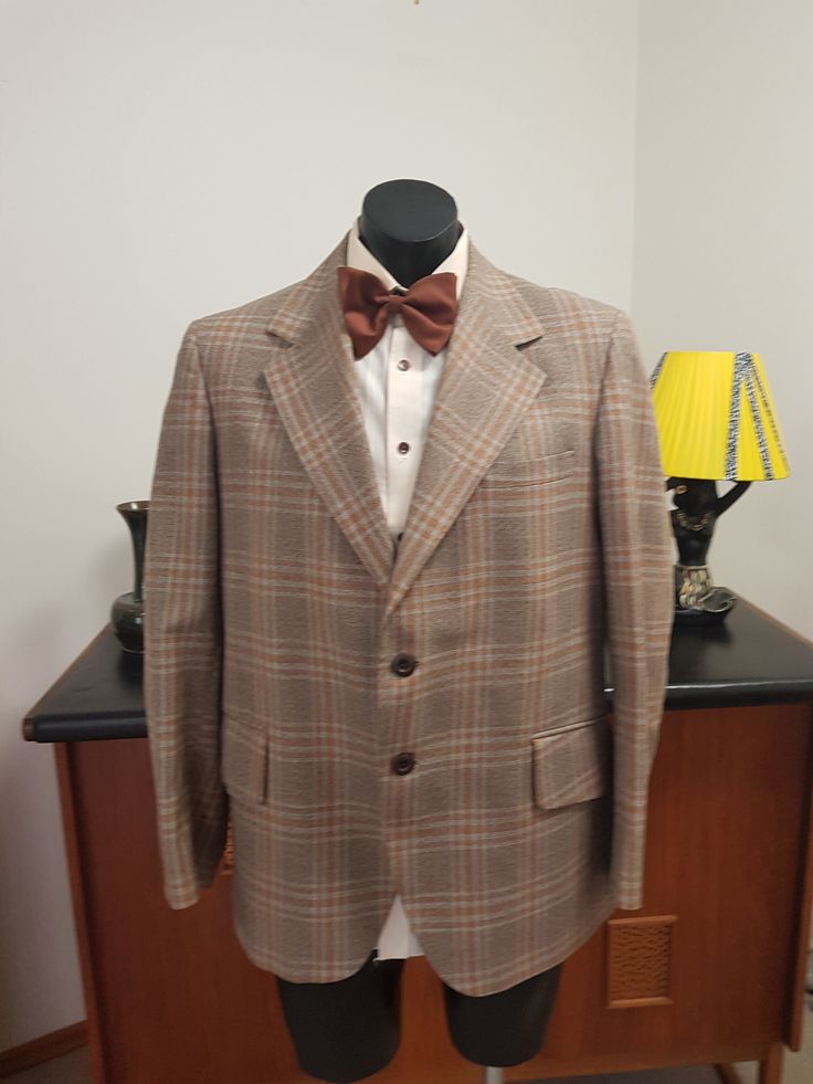 This jacket is from the 1970s in a pure wool and retailed by Fultons Mens wear store. The weight is all season in a light weight fabric from the English west country. Large lapels and flap pockets and two button closure  The condition is very good with no faults found EXCEPT that there is under arm staining in lining . Drycleaning should remove it And a dark mark on the sleeve  as in photo. Measurements are  Shoulder to shoulder 47cm Chest 116cm  Length shoulder to hem 74cm  Sleeves shoulder to Plaid Wool Sport Coat With Lapel Collar, Plaid Suits With Pockets For Fall, Fall Plaid Suits With Pockets, Brown Fall Suits With Lapel Collar, Semi-formal Plaid Sport Coat For Fall, Brown Wool Sport Coat With Flat Front, Retro Notch Lapel Suits For Fall, Retro Notch Lapel Fall Suits, Fall Retro Suits With Notch Lapel