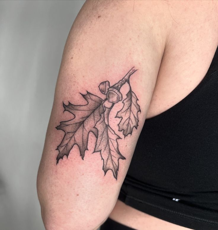 a woman's arm with a leaf tattoo on it