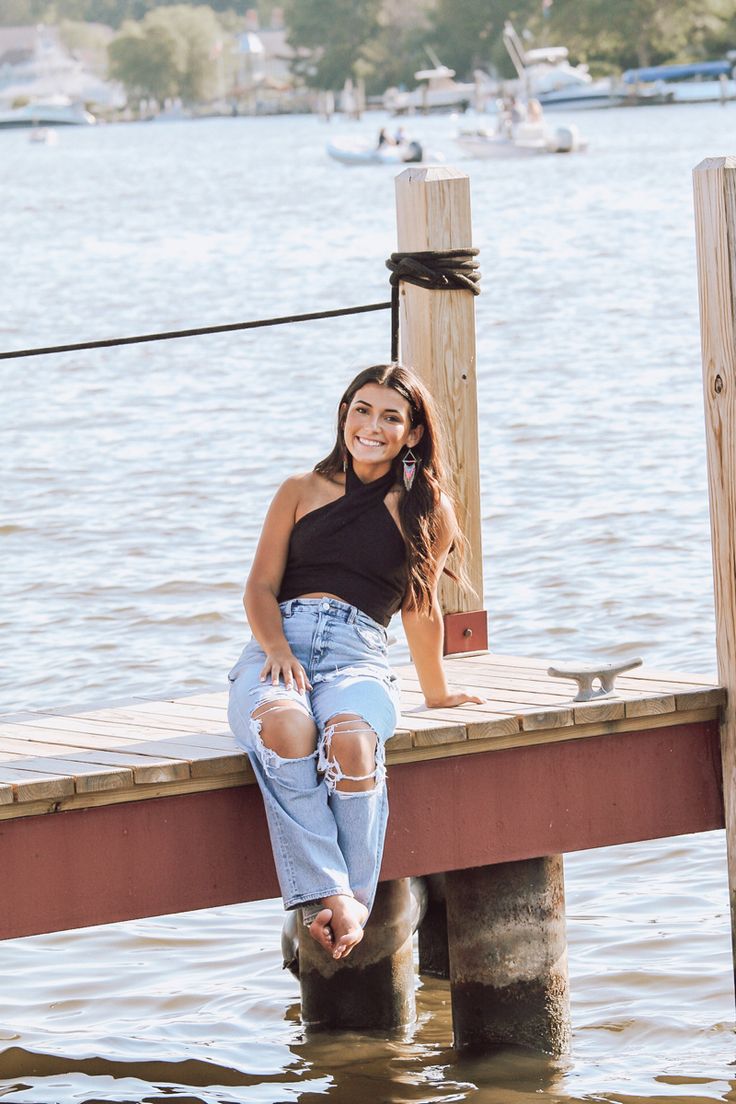 a beautiful woman sitting on top of a wooden dock