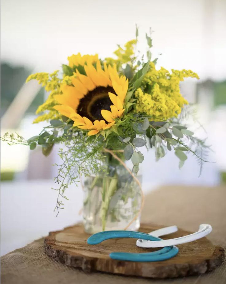 a vase filled with yellow flowers sitting on top of a wooden table next to scissors