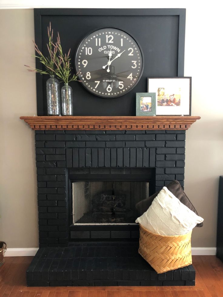 a fireplace with a clock on the wall above it and a basket next to it