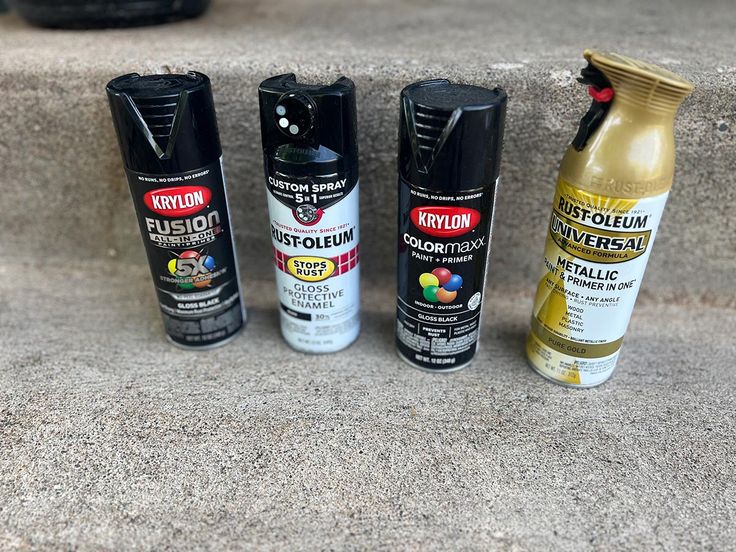 four different types of spray paint sitting on the ground