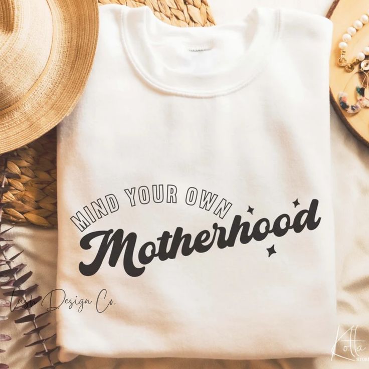 a t - shirt that says mind your own motherhood on it next to straw hats