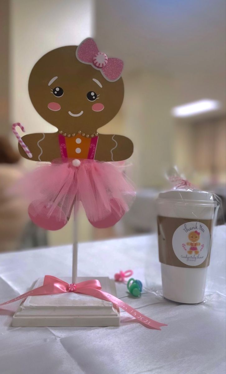 a table topped with a cup and a paper doll