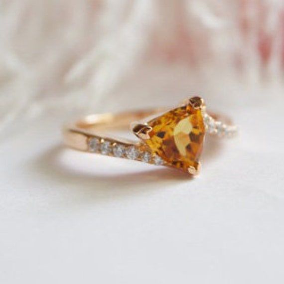 a yellow diamond ring sitting on top of a white cloth