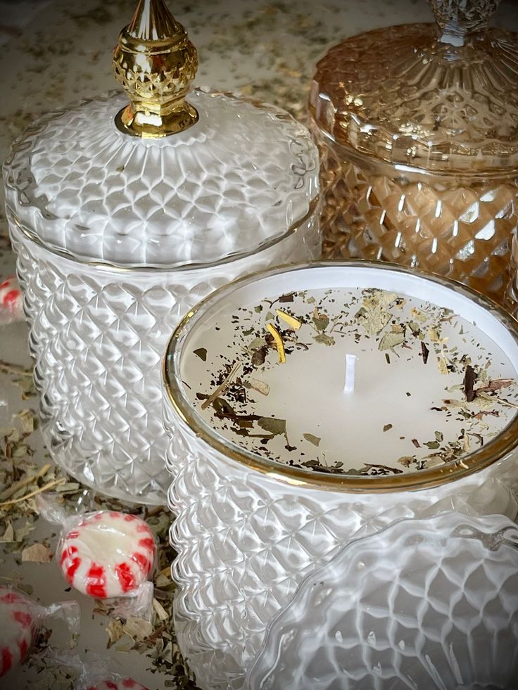 two glass jars with candles inside on a table