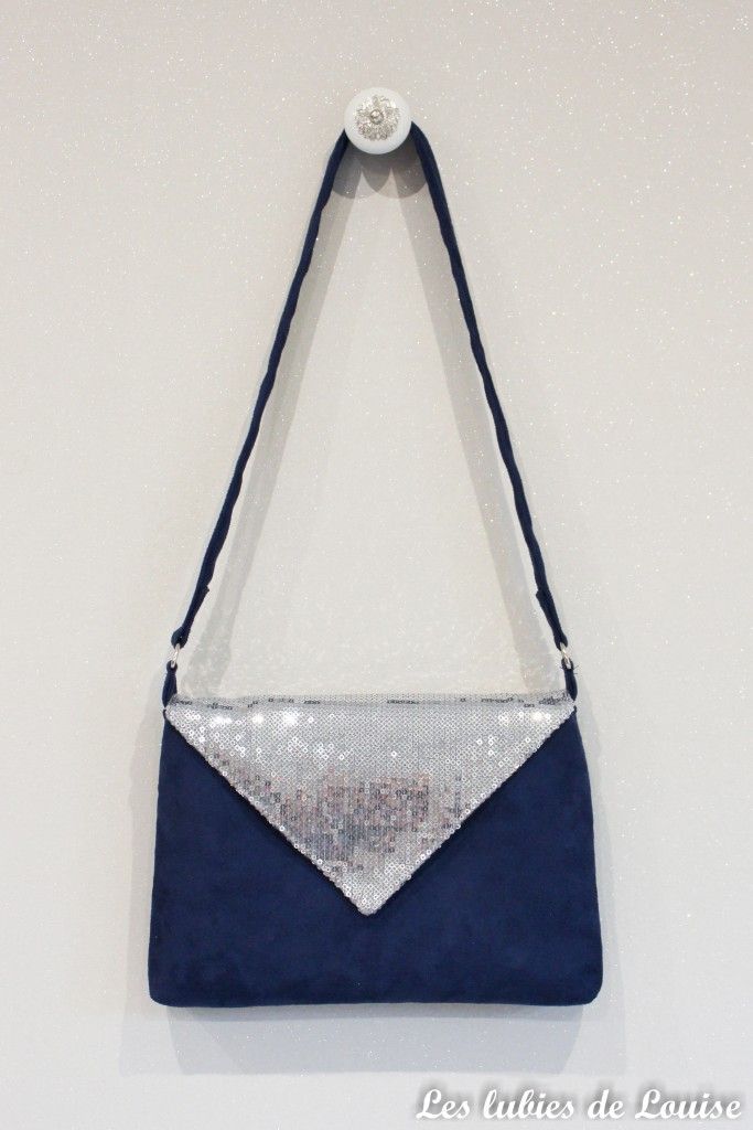 a blue and silver purse hanging on the wall with sequins attached to it