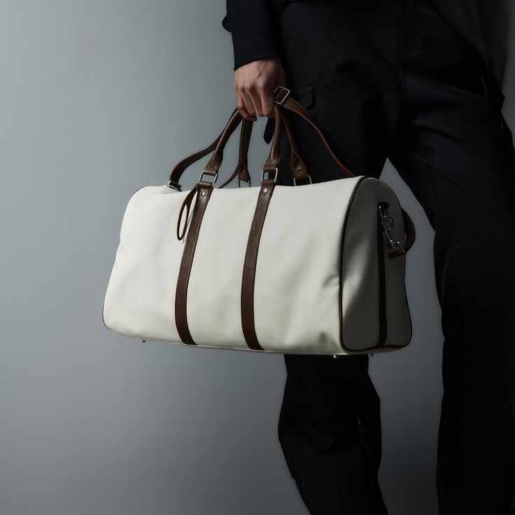 The Modern Canvas Duffle Bag effortlessly blends contemporary style with superior craftsmanship, making it a must-have for both travel and everyday use. Constructed from premium cotton canvas, this bag features PU leather accents that add a touch of sophistication and durability. The base of the bag is reinforced with four rivets, providing extra protection against wear and tear and extending its lifespan. Designed for versatility, it includes a detachable strap, allowing you to carry it as a cr Canvas Duffle Bag With Leather Trim For On-the-go, Luxury White Rectangular Canvas Bag, White Shoulder Bag With Leather Trim For On-the-go, Luxury White Canvas Bag For Daily Use, Luxury Large Capacity White Satchel, Modern Leather Canvas Bag For On-the-go, Luxury White Canvas Bag For Everyday, White Large Capacity Travel Bag For Everyday, Modern White Canvas Bag For Everyday