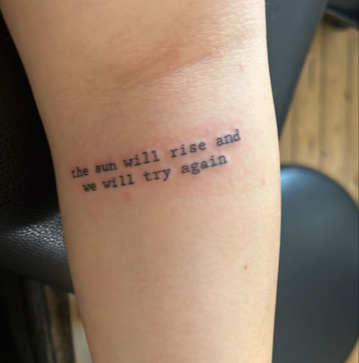 a tattoo saying the sun will rise and we will try again on someone's arm