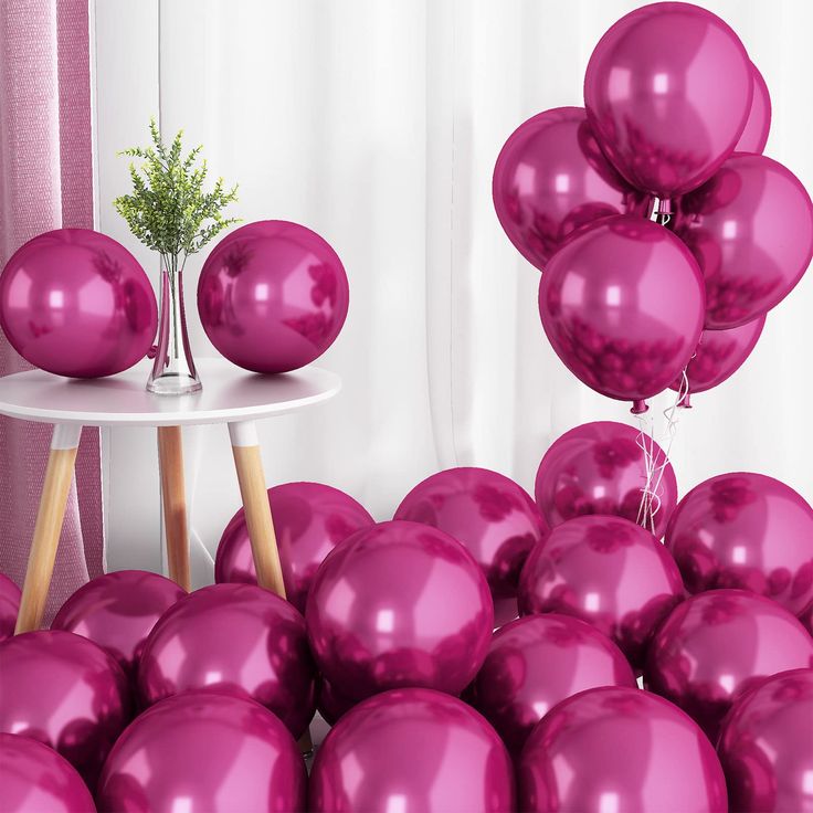 a bunch of pink balloons sitting on top of a table next to a white table