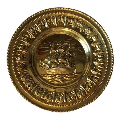 a gold plate with a ship on it