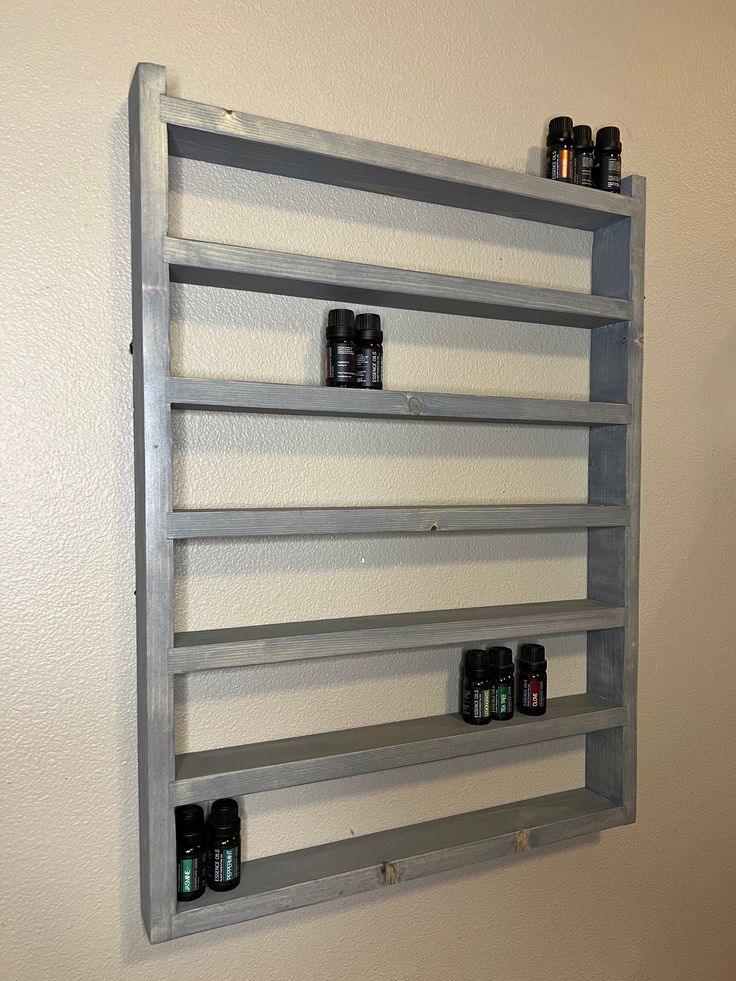 a wall mounted shelf with several bottles on the top and bottom shelves above it, in front of a white wall