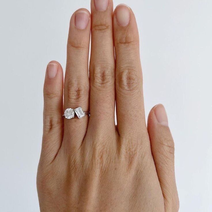 a woman's hand with a diamond ring on her left and the middle finger