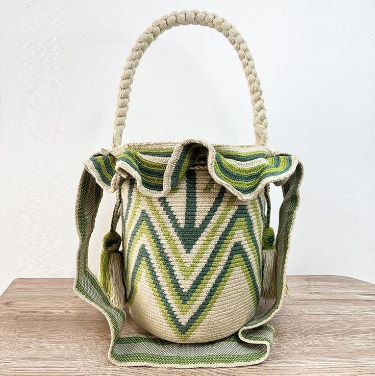 a green and white handbag sitting on top of a wooden table next to a wall