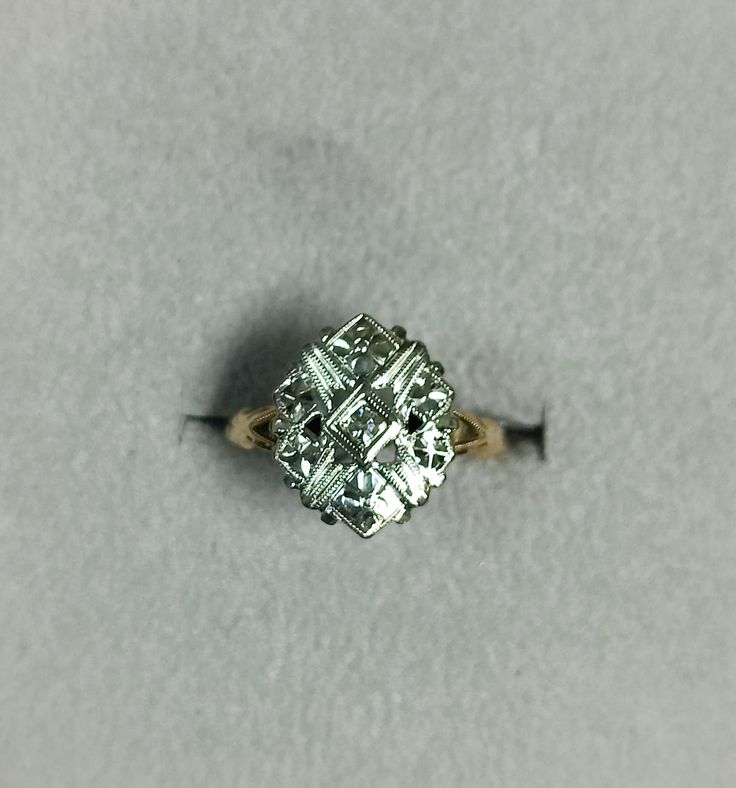 an old diamond ring sitting on top of a gray surface with the center stone missing