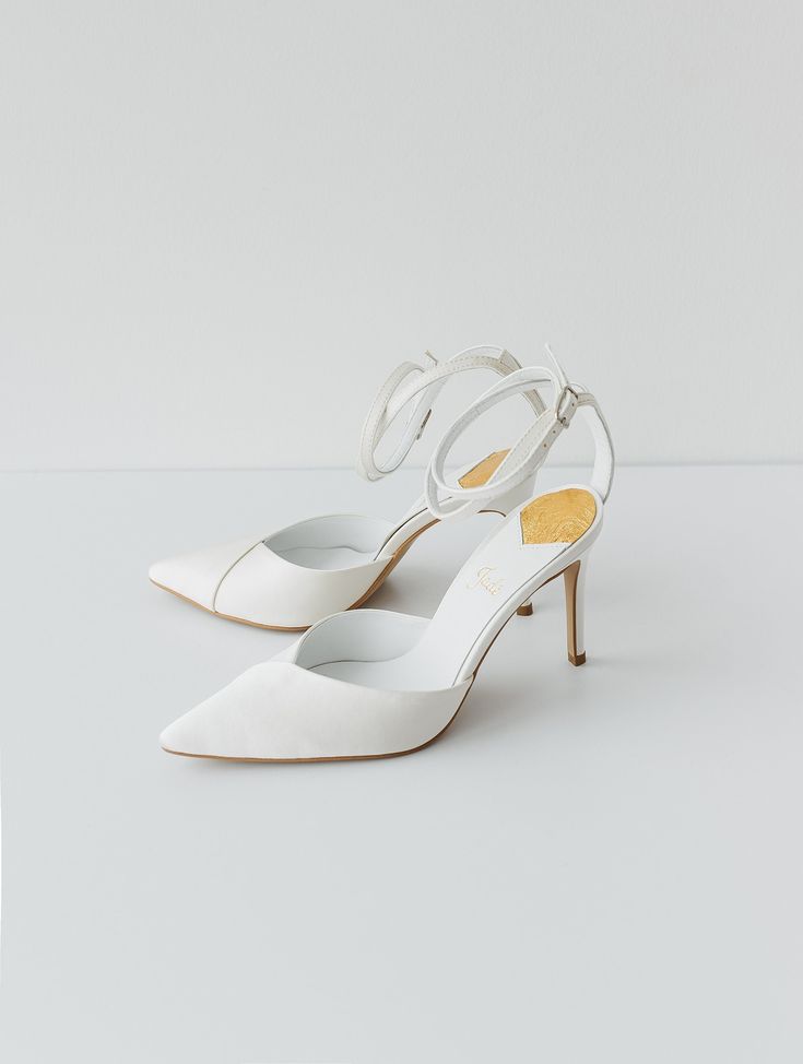 a pair of white high heeled shoes sitting on top of a white table next to each other