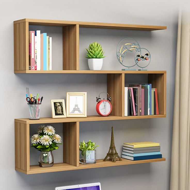 a laptop computer sitting on top of a pink book shelf next to a vase with flowers