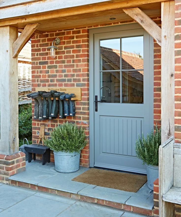 the front door to a brick house with boots hanging on it's hooks and potted plants