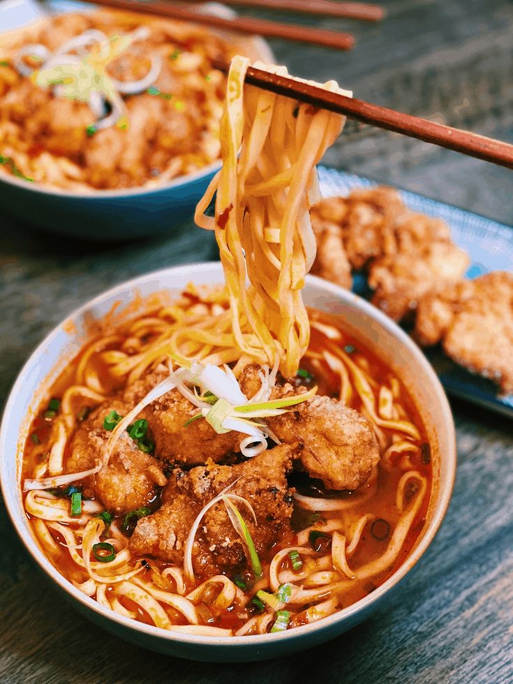 a bowl of noodles and meat with chopsticks sticking out of it, ready to be eaten