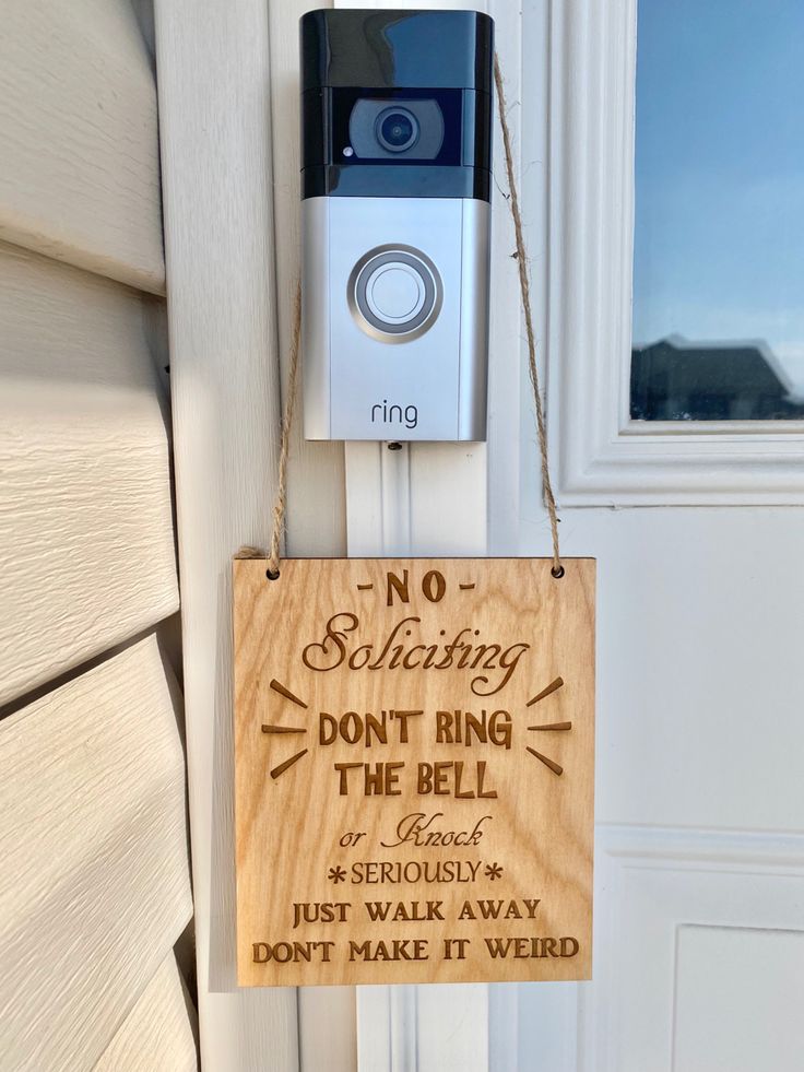 a wooden sign hanging from the side of a door with a camera attached to it