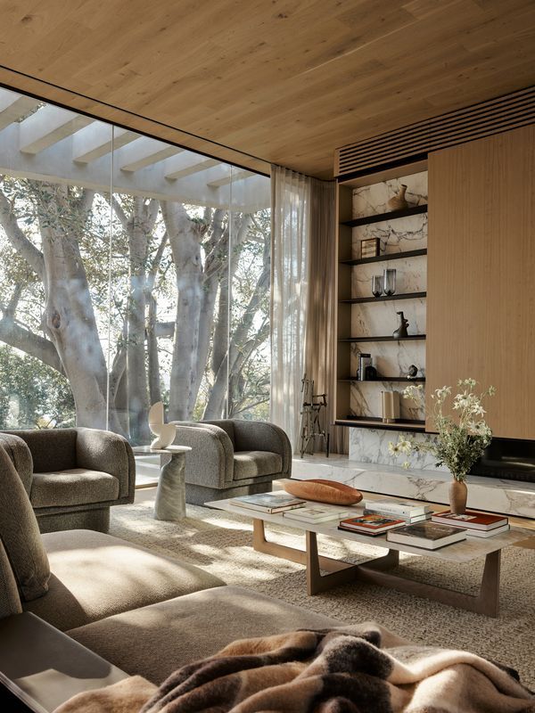 a living room filled with furniture and a large window overlooking the trees in front of it