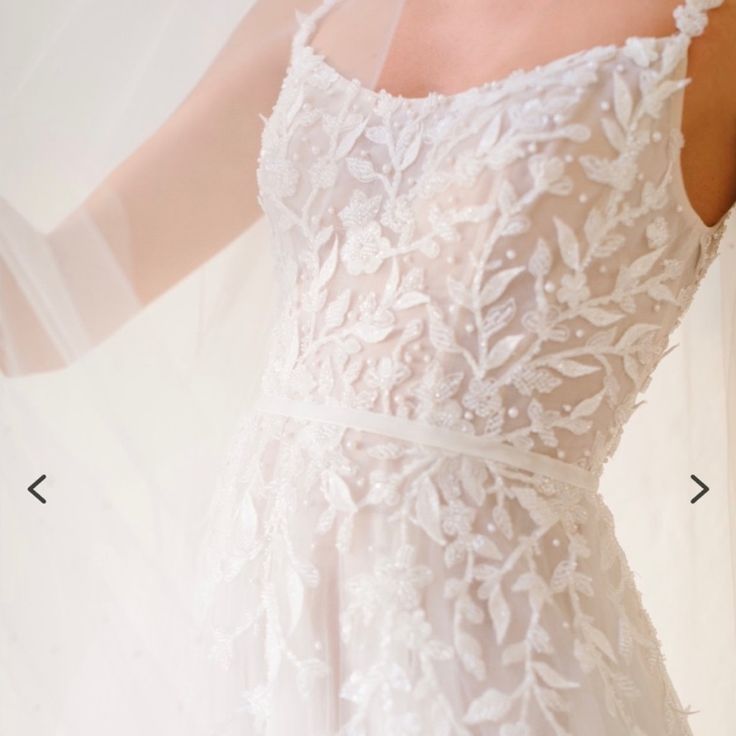 the back of a wedding dress with white flowers on it and an arrow pointing to the side