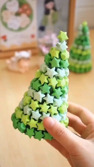 a hand holding a small green and white christmas tree made out of star shaped objects