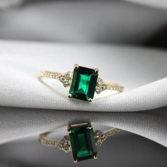 Handmade by an inspired jewelry artist team with decades of experience in the craft of jewelry making.Each gemstone, each diamond is carefully picked.Using only the finest raw materials and the highest industry standard in manufacturing, design and finish.A beautiful vintage inspired piece handmade just for you.An impressive radiant cut emerald brings rich color to this ring, contrasted by brilliant diamond side stones set in a shimmering 10,14 or 18 Karat gold setting.Ring Features:- Gemstone i Green Emerald Diamond Ring With Accents, Timeless Emerald Diamond Wedding Ring, Classic Emerald Ring For Promise, Timeless Emerald Anniversary Ring, Timeless Emerald Wedding Anniversary Ring, Timeless Emerald Gemstone Wedding Ring, Timeless Emerald Ring With Accent Stones For Promise, Exquisite Brilliant Cut Emerald Promise Ring, Heirloom Diamond Emerald Promise Ring