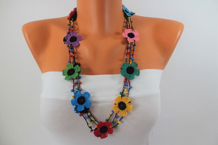 a woman wearing a multicolored necklace with flowers on the front and back of it