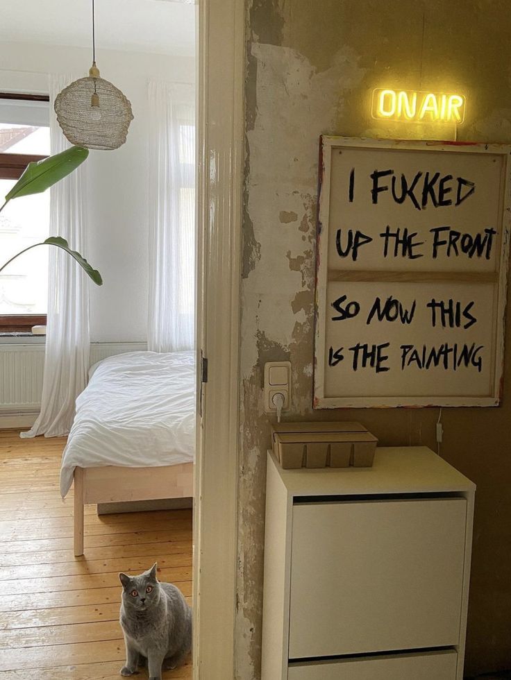 a cat sitting on the floor next to a bed