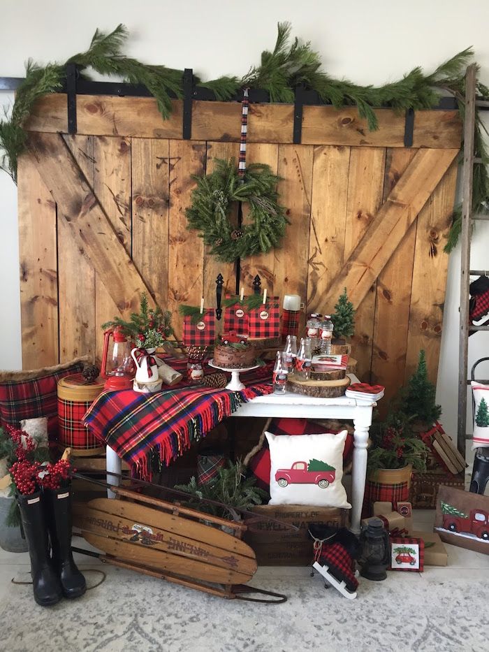 a christmas display in front of a wooden wall with plaid and pine wreaths on it