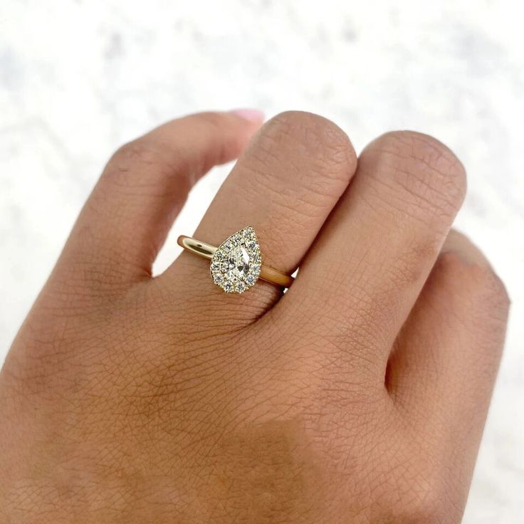 a woman's hand with a diamond ring on top of her finger, in front of a white background