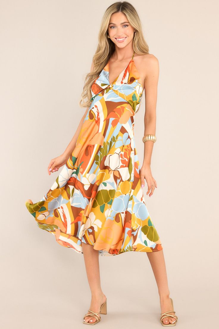 This multi-colored dress features a v-neckline, a self-tie feature at the back of the neck, an open back, a discrete back zipper, a twisted bust detail, and a colorful pattern.