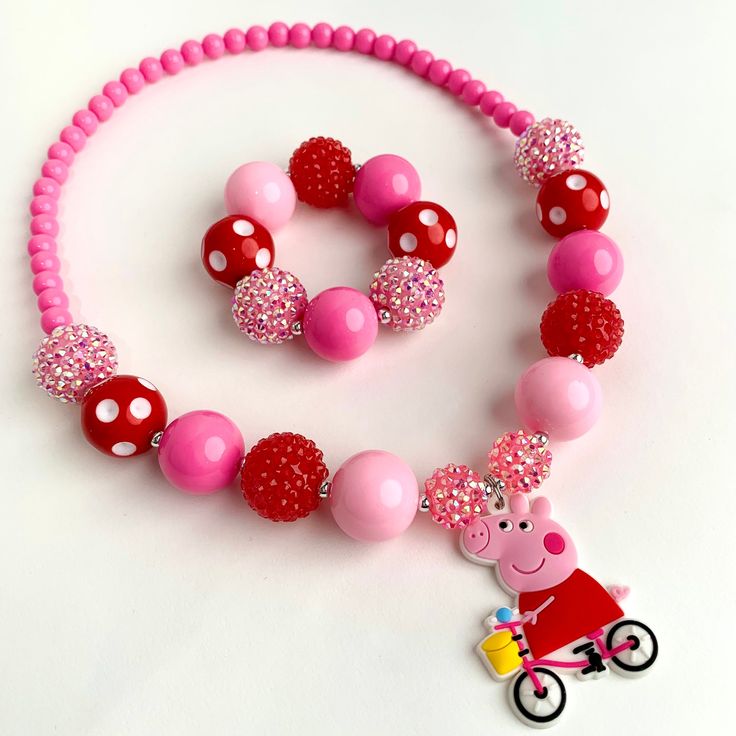 Includes Necklace and Bracelet  Necklace and bracelet are made with Stretch Magic Elastic. No need for clasps! Peppa Pig Pendant made of PVC Pink and red 20mm chunky beads  Please message me if you would like it made longer or shorter. I can add or remove a bead. Perfect for a photo prop or dress up! 👗  Recommend Ages: 3 and up Please supervise children with small parts Valentine's Day Playful Beaded Jewelry, Pink Plastic Birthday Jewelry, Pink Plastic Jewelry For Birthday, Playful Round Beads Jewelry For Valentine's Day, Playful Valentine's Day Jewelry With Round Beads, Handmade Red Necklaces For Birthday, Handmade Red Necklace For Birthday, Playful Red Jewelry For Birthday, Playful Red Nickel-free Jewelry