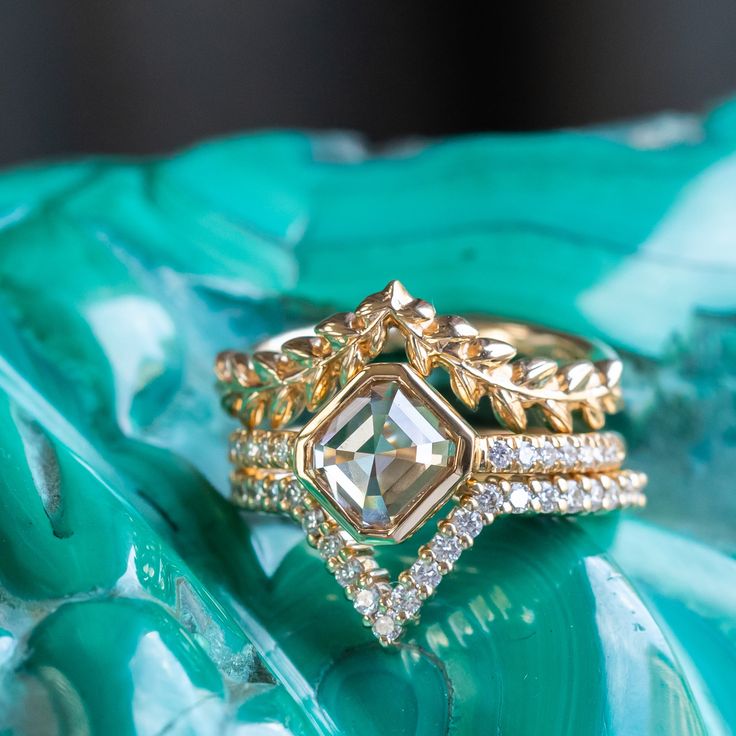 a close up view of two rings on top of a green leafy surface with diamonds