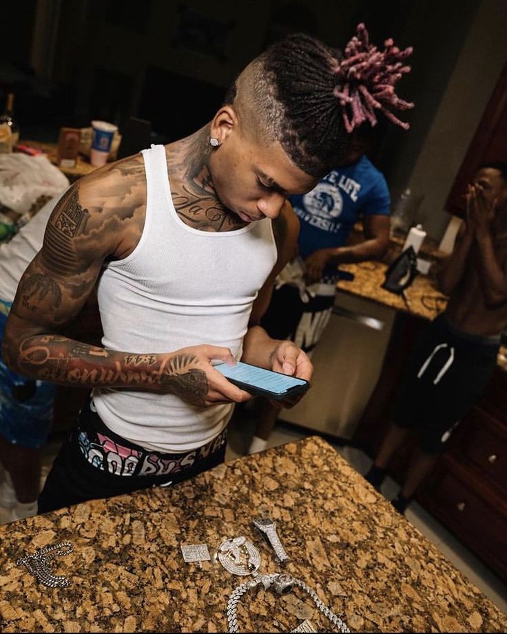 a man with tattoos on his arm looking at a cell phone