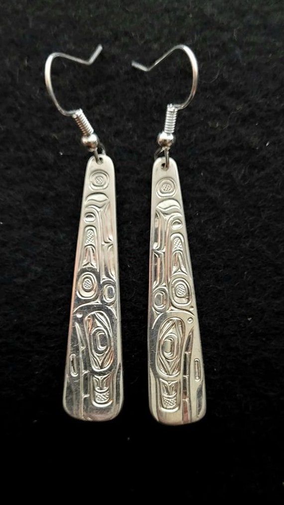 On offer is a made to order West Coast Namgis First Nation Hand carved pair of sterling silver ''Orca'' earrings. by World renowned master carver Joe R. Wilson with his depiction of Orca in the style of the Namgis, Kwakiutl First Nation. Initialed by Joe. Fine example of Indigenous Art from the Northwest Coast First Nations of Canada. If you want to see more of my items, google ( The Kanata Shop ) PLEASE NOTE THAT THIS IS A CUSTOM RECREATED HAND CARVED ITEM THAT WILL HAVE SLIGHT, SUBTLE DIFFEREN Engraved Sterling Silver Drop Earrings, Engraved Teardrop Earrings For Gift, Artisan Carved Sterling Silver Jewelry, Carved White Gold Sterling Silver Jewelry, Polished Sterling Silver Earrings As A Gift, Engraved Sterling Silver Dangle Jewelry, Gift Long Drop Earrings With Polished Finish, Traditional Polished Earrings As Gift, Traditional Polished Earrings For Gift