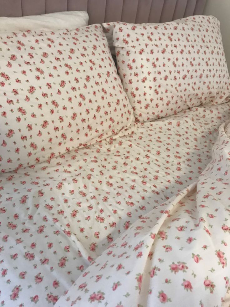 an unmade bed with white and red flowers on it