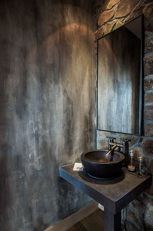 a bathroom sink sitting under a mirror next to a stone wall