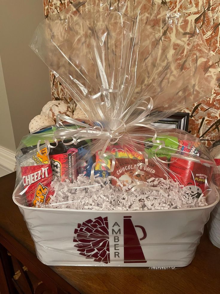 a white basket filled with lots of food and drinks on top of a wooden table