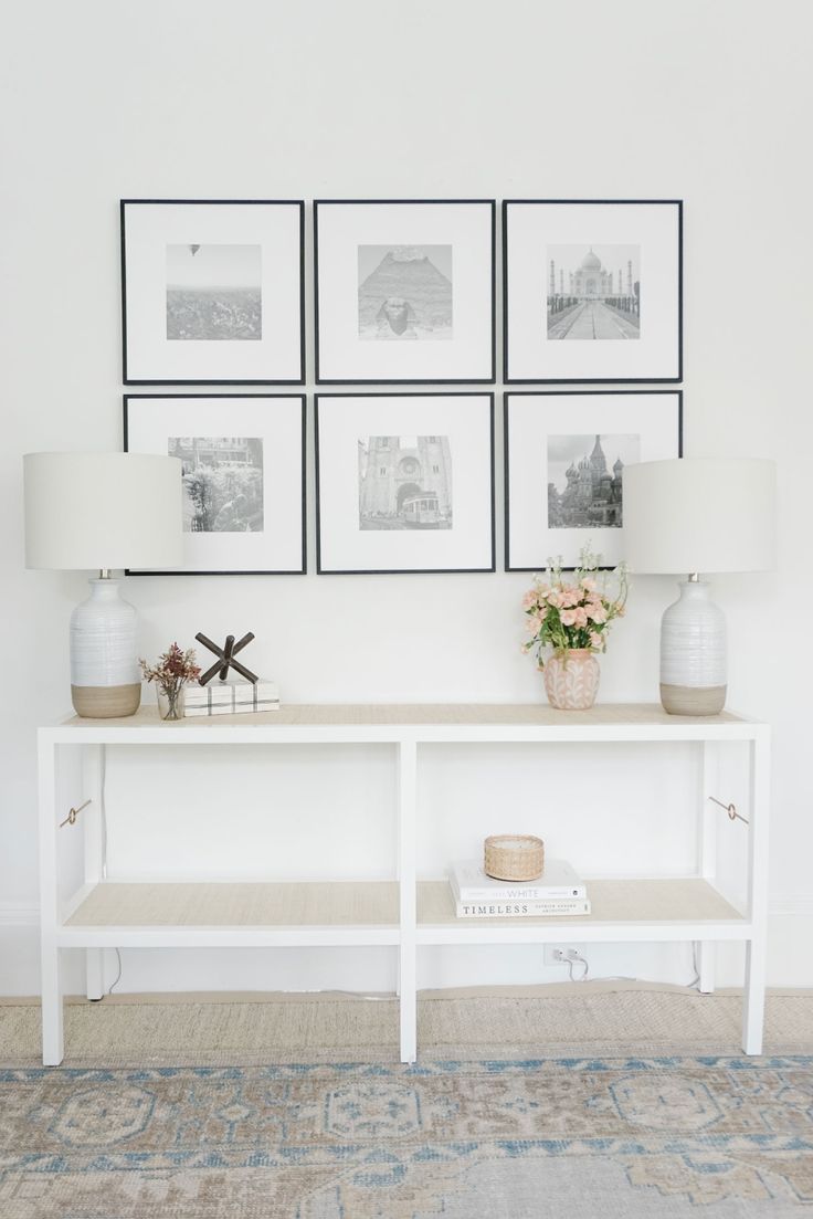 a white table topped with vases and pictures next to a wall mounted on the wall